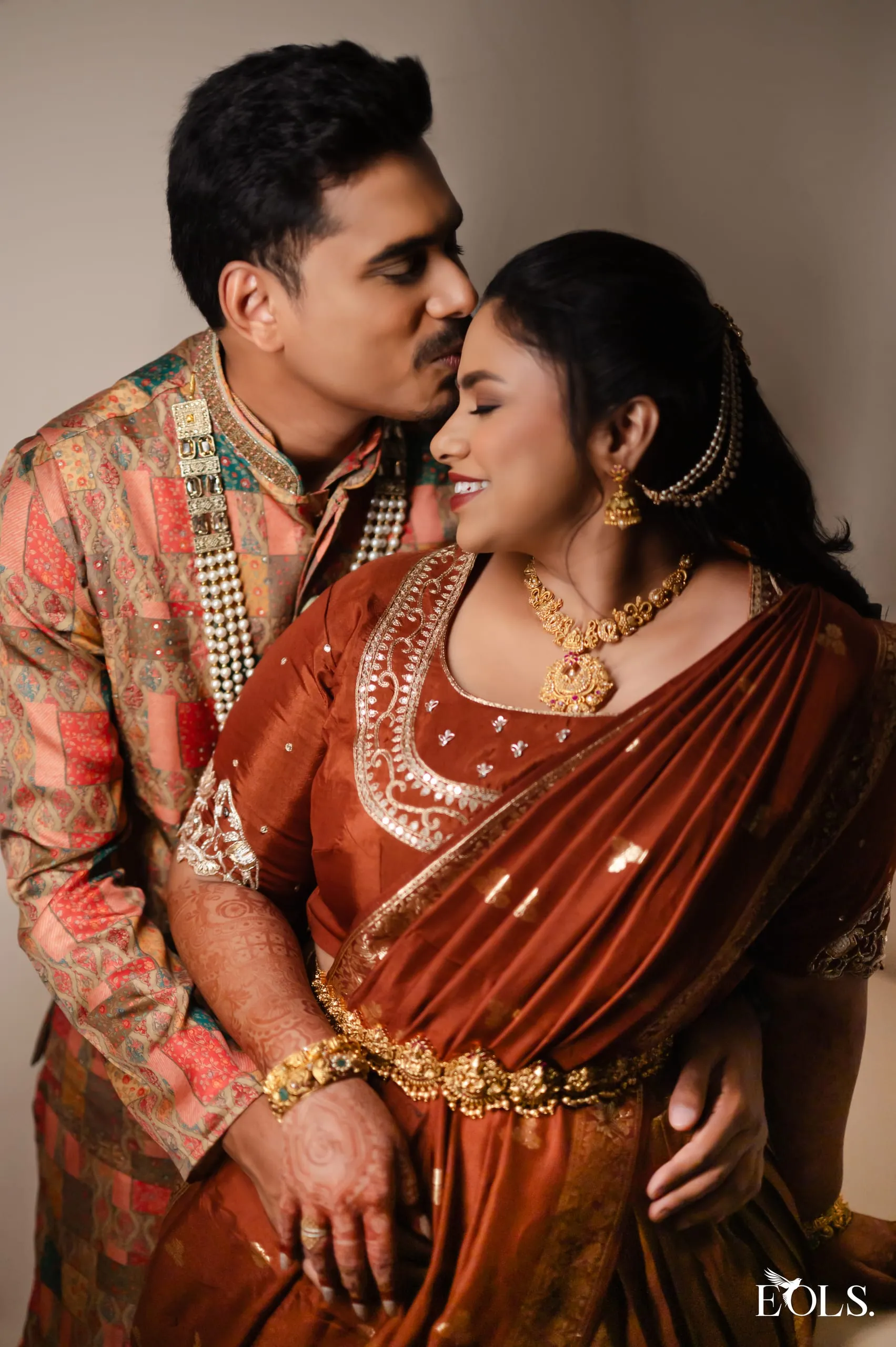 Gautham kissing Swathi on the forehead, she in a copper silk saree