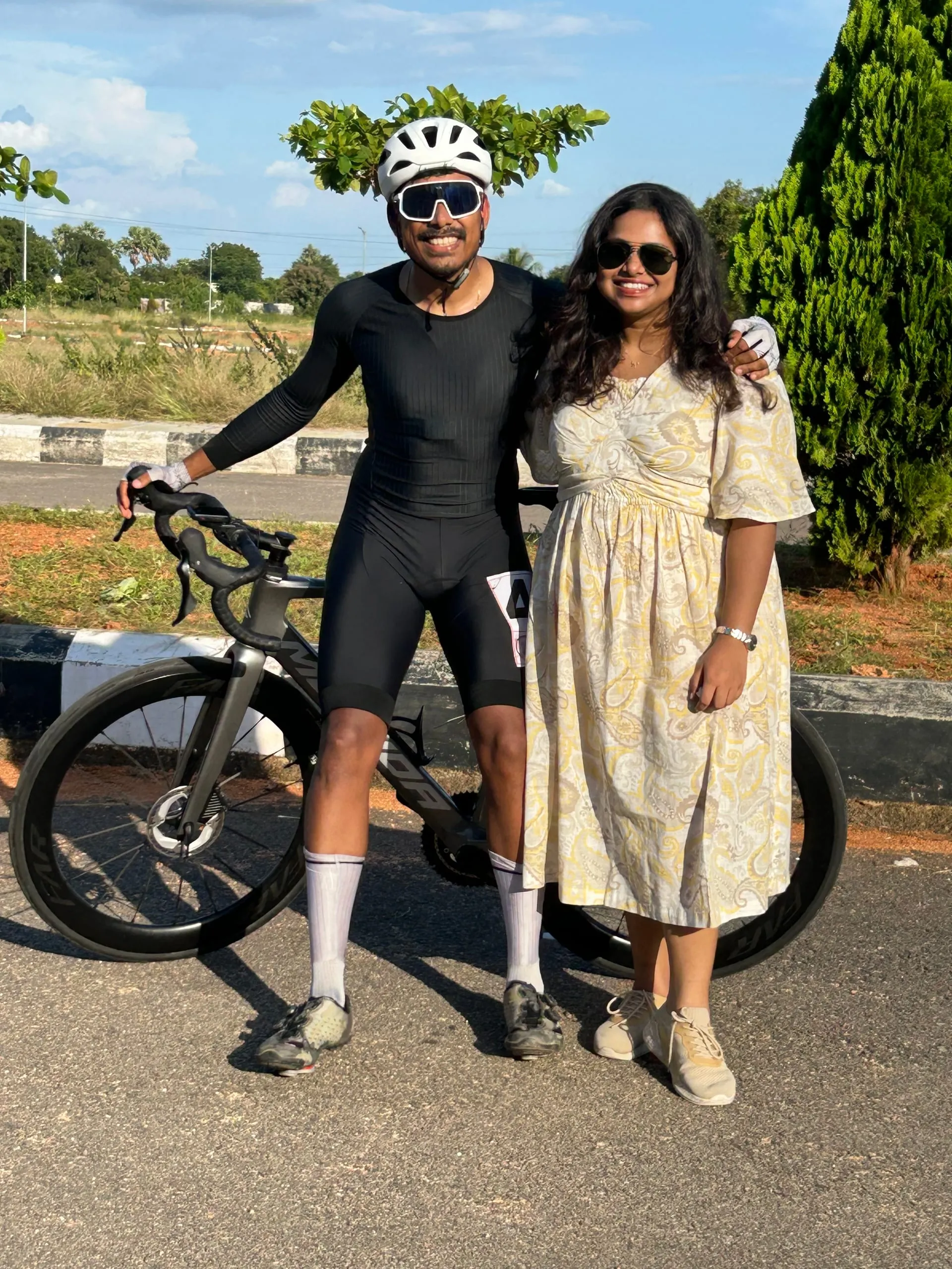 Gautham in cycling kit beside his road bike, Swathi next to him in a yellow dress