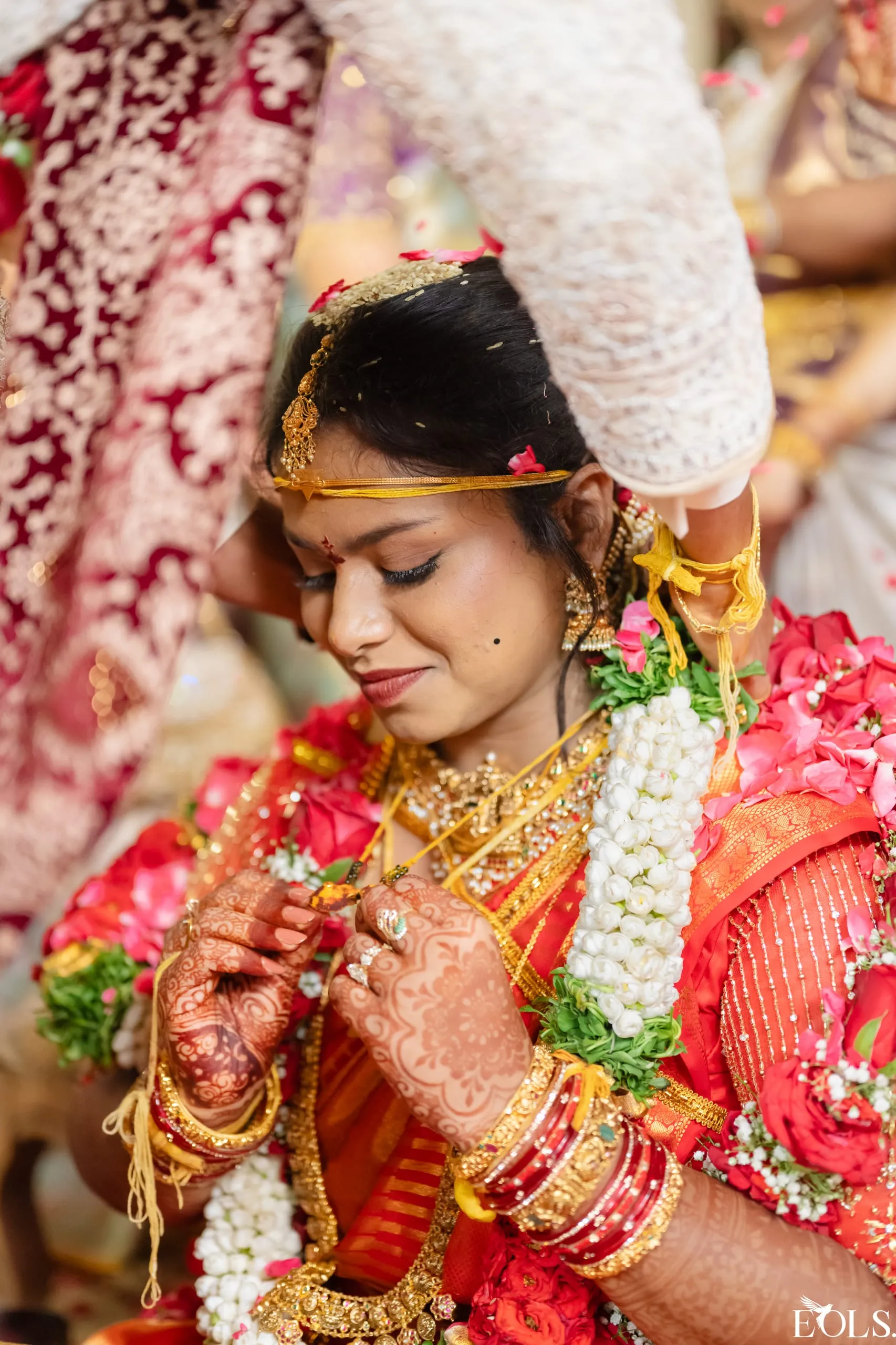 Close portrait of Swathi as a bride in red and gold with jasmine
