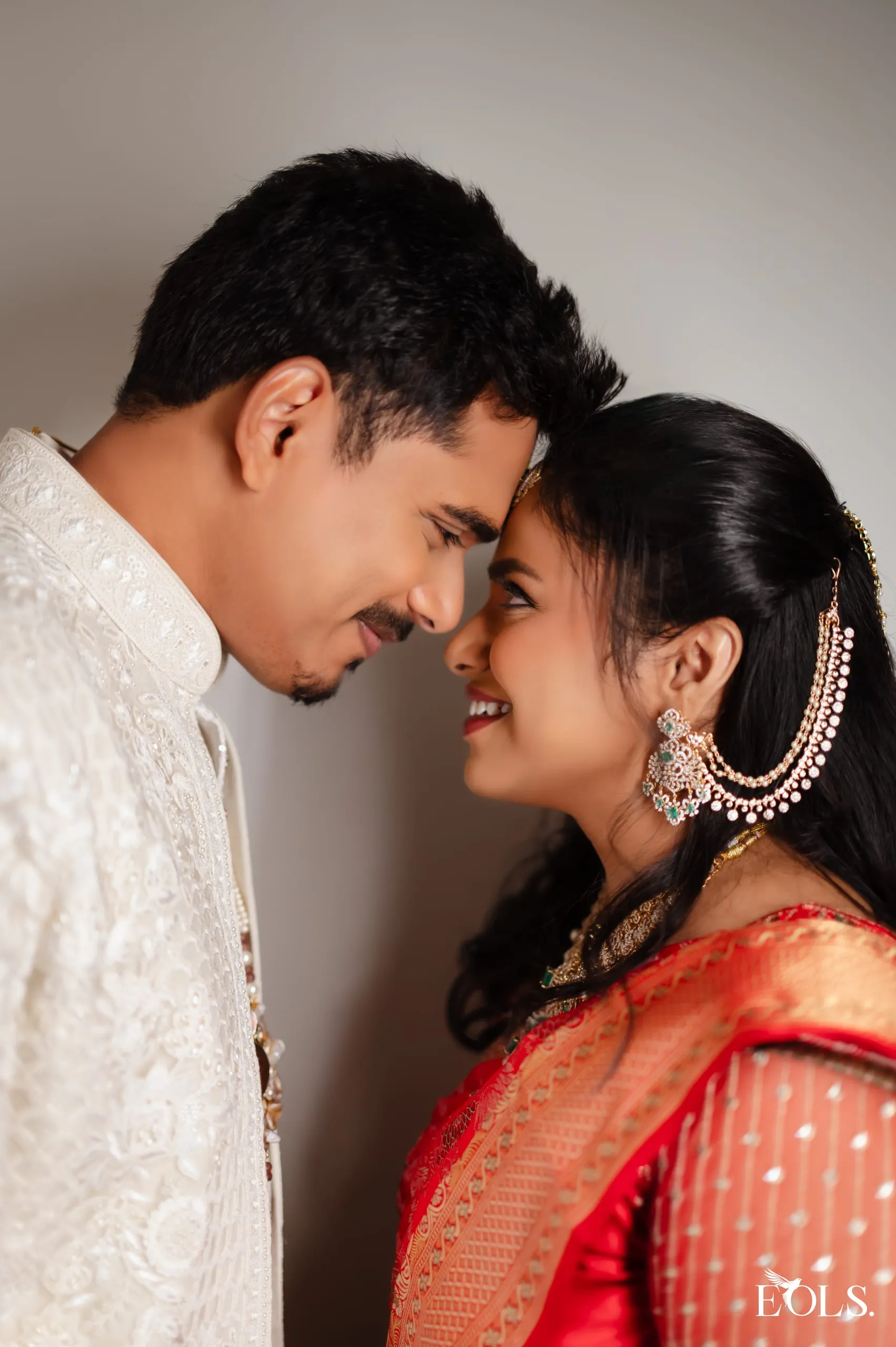 Swathi and Gautham resting foreheads together, both in cream