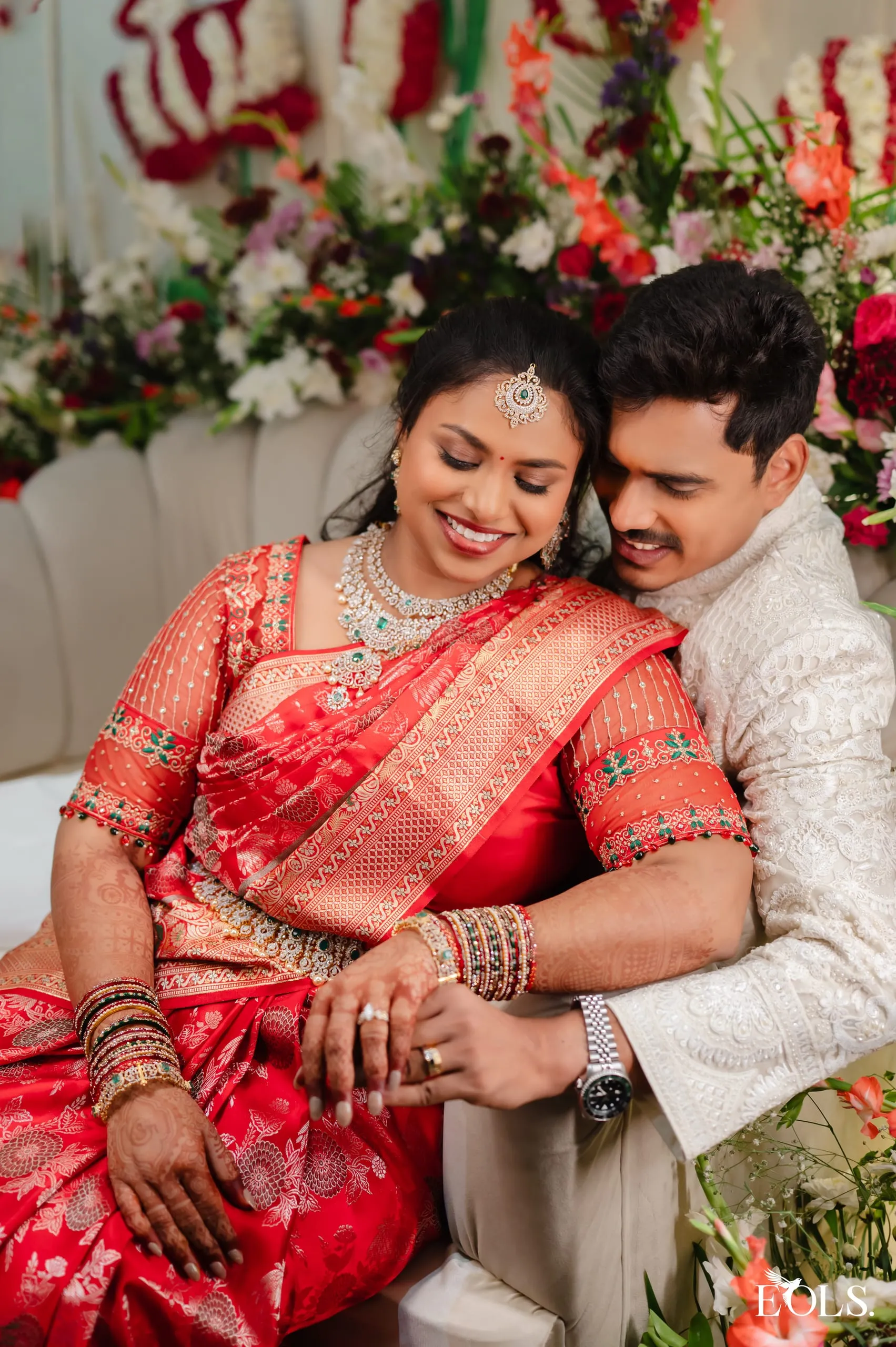 Swathi and Gautham seated, embracing, she in red